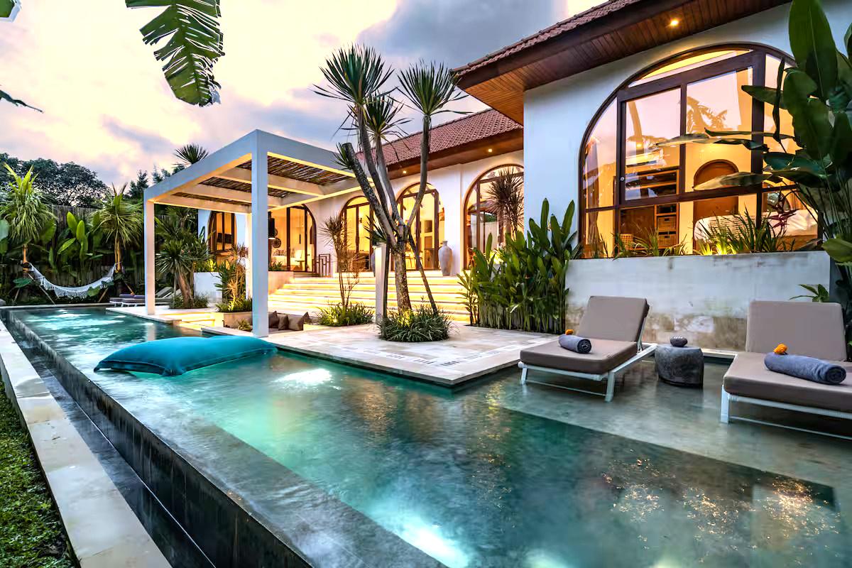 Bali villa with lit arches and pool at dusk